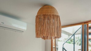 Una habitación con una mesa redonda de madera, una estatua de Buda, una lámpara de fibra y una escalera de caracol al fondo.