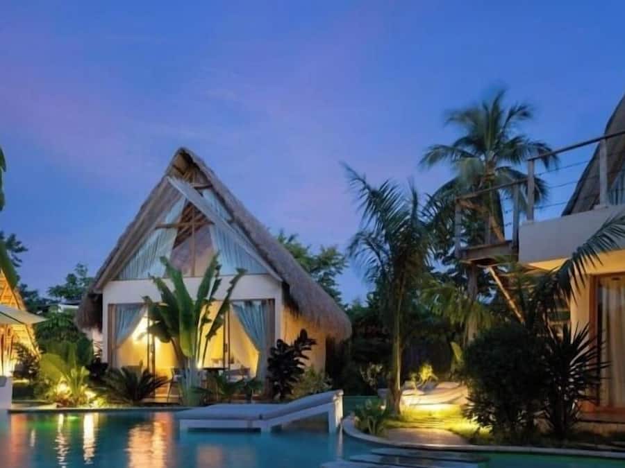 Un resort con piscina, palmeras y una construcción de techo de paja.