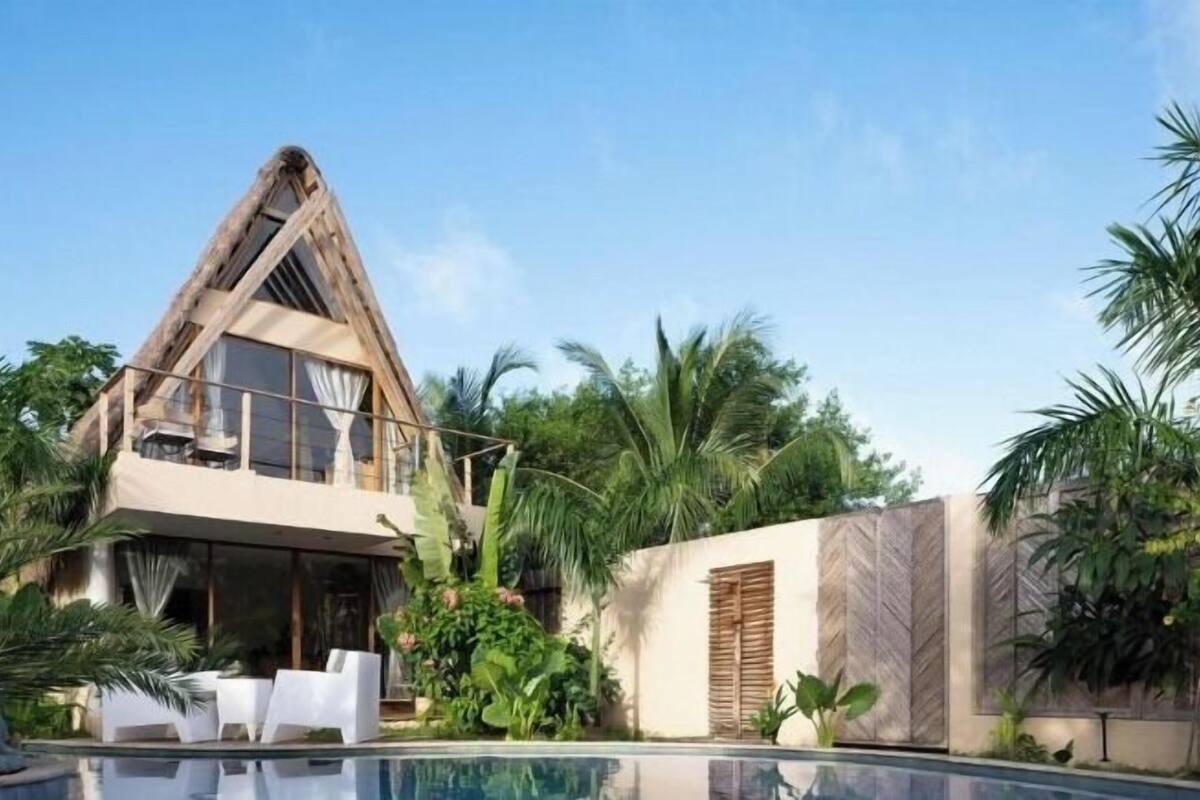 Una casa moderna con piscina, rodeada de plantas tropicales.