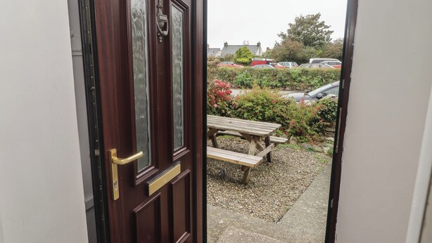 A wooden door with the number 44, leading to a garden area with a wooden bench and a gravel path. - Garth Cottage (Haverfordwest)