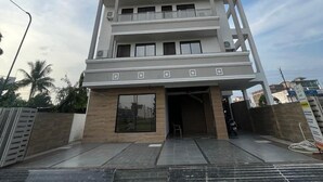 Un hôtel à plusieurs étages au design moderne, doté de balcons à chaque niveau et d’une entrée imposante.