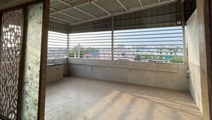 Un balcon spacieux offrant une vue sur le paysage urbain, un sol carrelé et une cloison décorative.