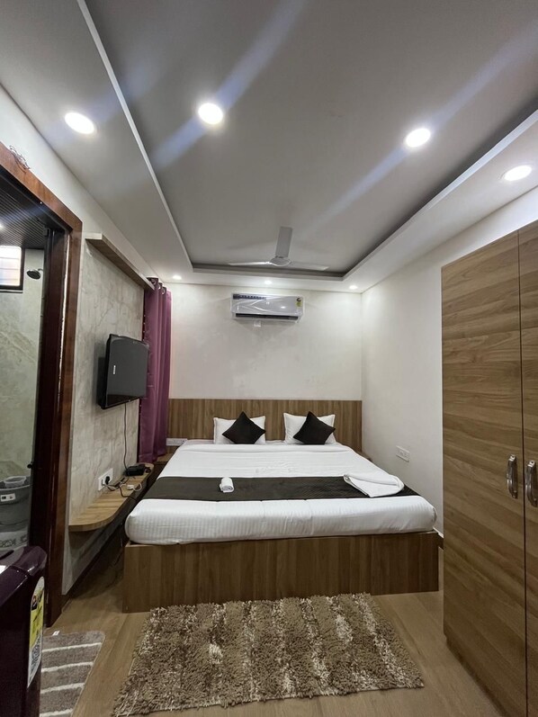 A modern hotel room with a bed, a television, an air conditioning unit, and a wardrobe. - SUKOON GRANDEUR  (Bhopal)