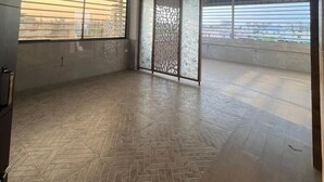 Une pièce spacieuse dotée d’un parquet à motifs en chevrons, de grandes fenêtres équipées de stores, d’un ventilateur de plafond et d’un paravent décoratif.