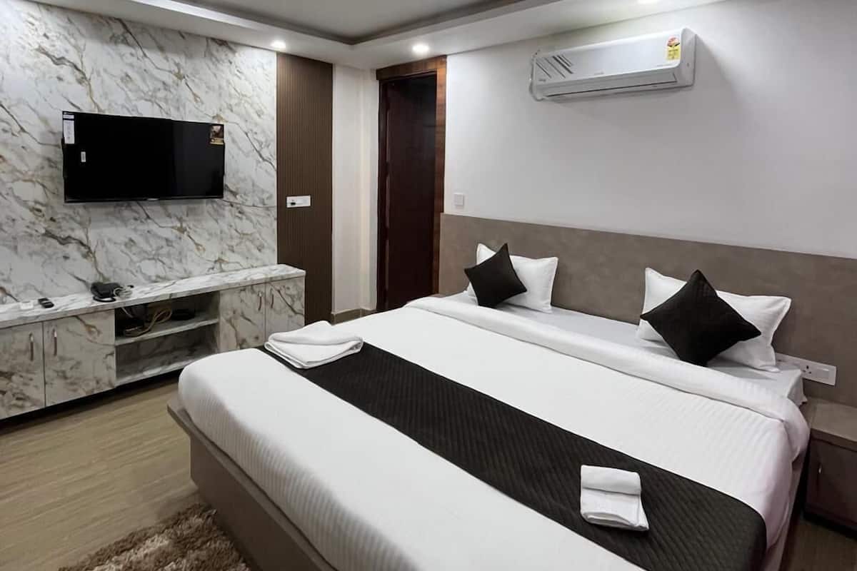 Een moderne hotelkamer met een groot bed, een flatscreen televisie aan de muur en een airconditioning.