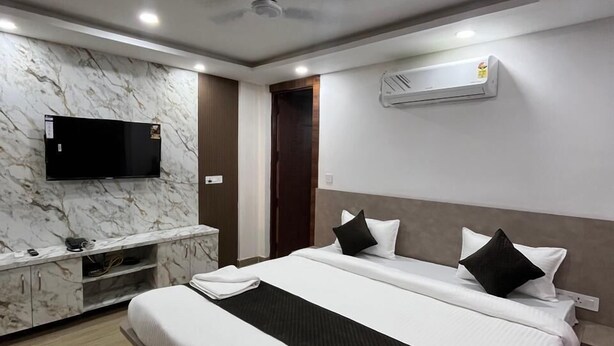 Une chambre d’hôtel moderne dotée d’un grand lit, d’un téléviseur à écran plat fixé au mur et d’un appareil de climatisation.