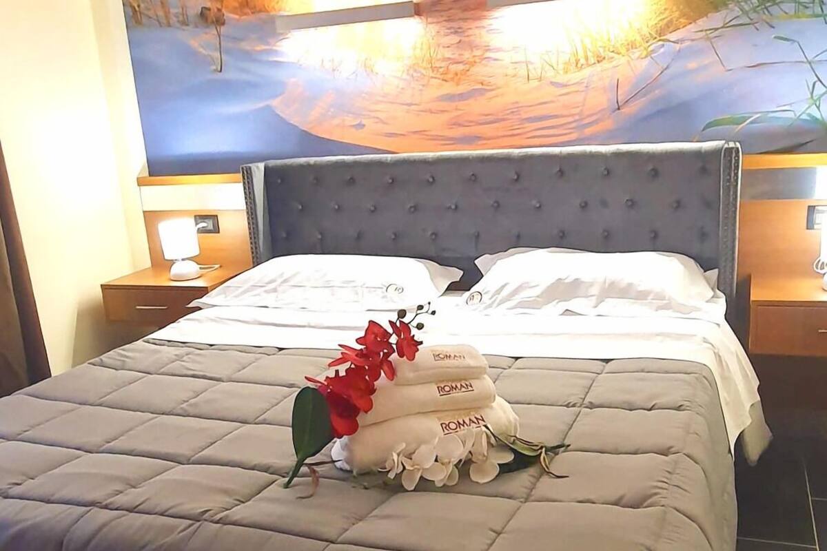 A hotel room with a large bed, a headboard, and a painting on the wall.