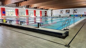 A large indoor swimming pool with multiple lanes, a diving board, and a spectator area. - Residence Roman (Pomezia)