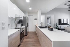 Una cocina moderna con armarios blancos, electrodomésticos de acero inoxidable y una isla central con fregadero.