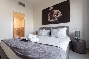 A modern hotel room with a bed, a nightstand, a lamp, and a large painting on the wall. - Jumeirah Golf Estates Sleeps 2 With Balcony Views (Dubai)