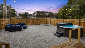 A backyard with a hot tub, outdoor seating, and string lights. - Modern Indy Retreat with Hot Tub, Outdoor Oasis, Prime location to Lucas Oil (Indianapolis)