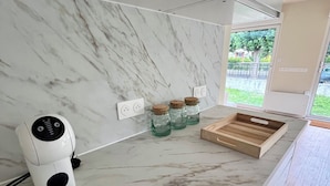 Une cuisine moderne avec un plan de travail en marbre, un appareil à café intégré et des bocaux accrochés au mur.