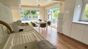 Une cuisine moderne dotée d’un grand évier, d’un plancher en bois et d’un coin repas avec une table et des chaises.