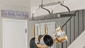 Uma cozinha com um armário de madeira, bancada e panelas penduradas.