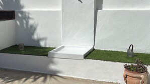 Un mur blanc avec une petite fenêtre et un objet en treillis métallique près de la base.