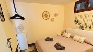 Une chambre à coucher comprenant un lit, une table de chevet, une lampe suspendue et un élément de décoration murale.