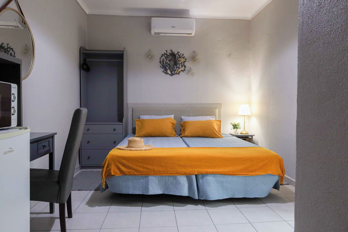 Ein Schlafzimmer mit Bett, Schreibtisch, Stuhl, Kommode und einer Wand-Klimaanlage.