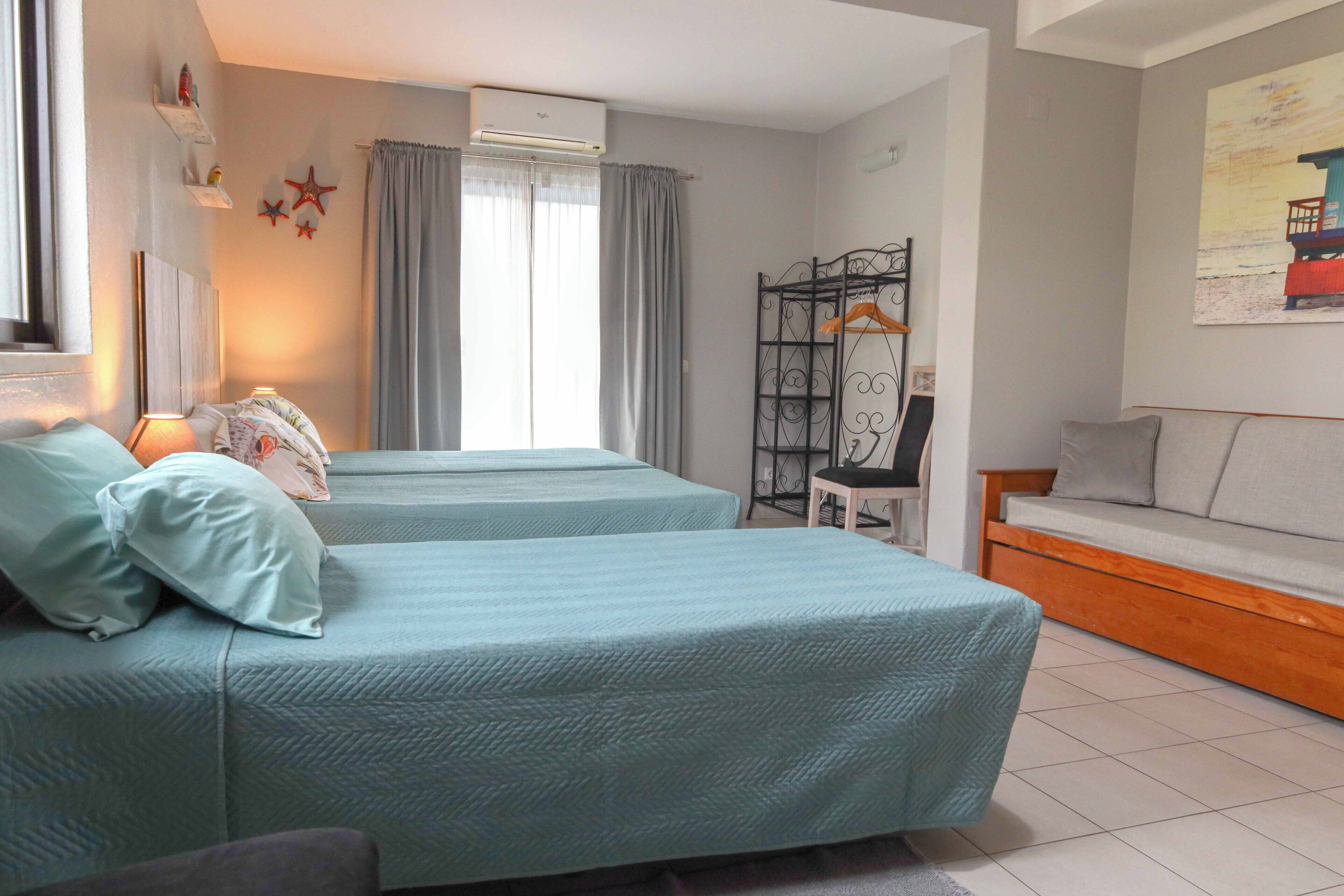 Una habitación con dos camas, un sofá, una silla y un cuadro en la pared.