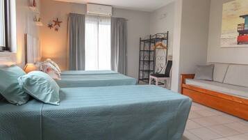 Una habitación con dos camas, un sofá, una silla y un cuadro en la pared.