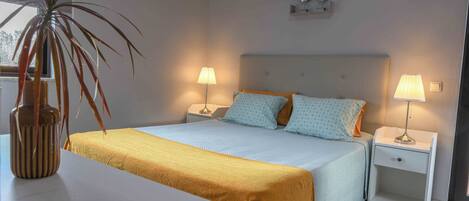 A neatly arranged bedroom with a bed, bedside tables, lamps, and a potted plant.