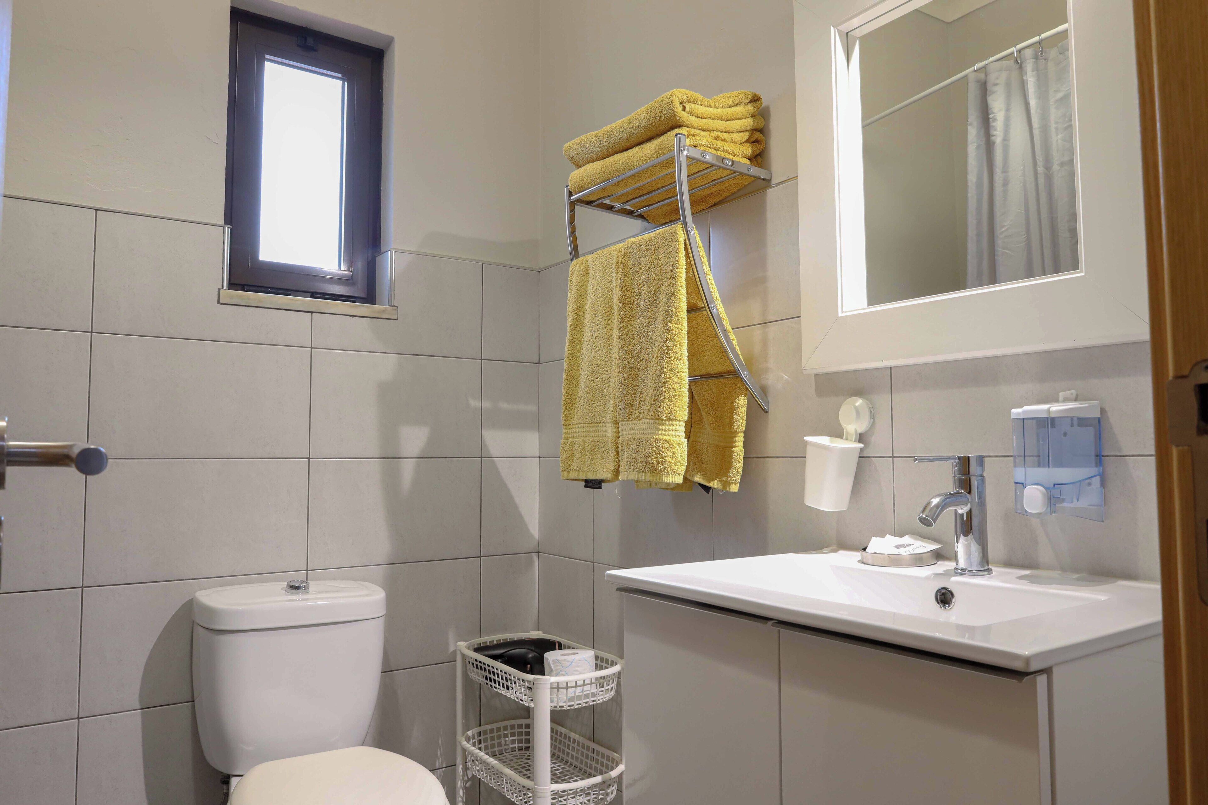 Ein Badezimmer mit Toilette, Waschbecken und einem Handtuchhalter mit Handtüchern.