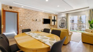 Una sala de estar moderna con pared de piedra, una mesa redonda de madera y sofás amarillos.