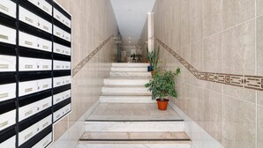 Una escalera de mármol con una planta en maceta, una barandilla de metal y una pared con armarios.