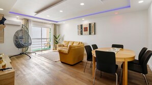 Una sala de estar moderna con sofá, mesa de comedor, sillas, una silla colgante y obras de arte en la pared.