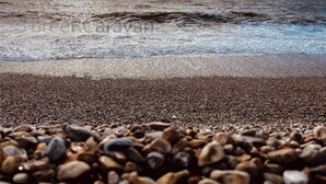 Ein Strand mit Kieselsteinen und Wellen.
