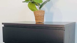 A dark wooden dresser with three drawers and a woven basket containing a green plant on top. - Centrally + Conveniently Located (Providence)