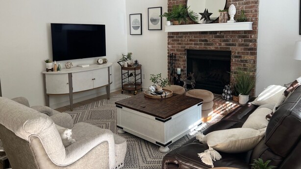 A living room with a brick fireplace, a flat-screen TV, a coffee table, and a sofa. - Adorable Golf Course House in Tallahassee (Tallahassee)