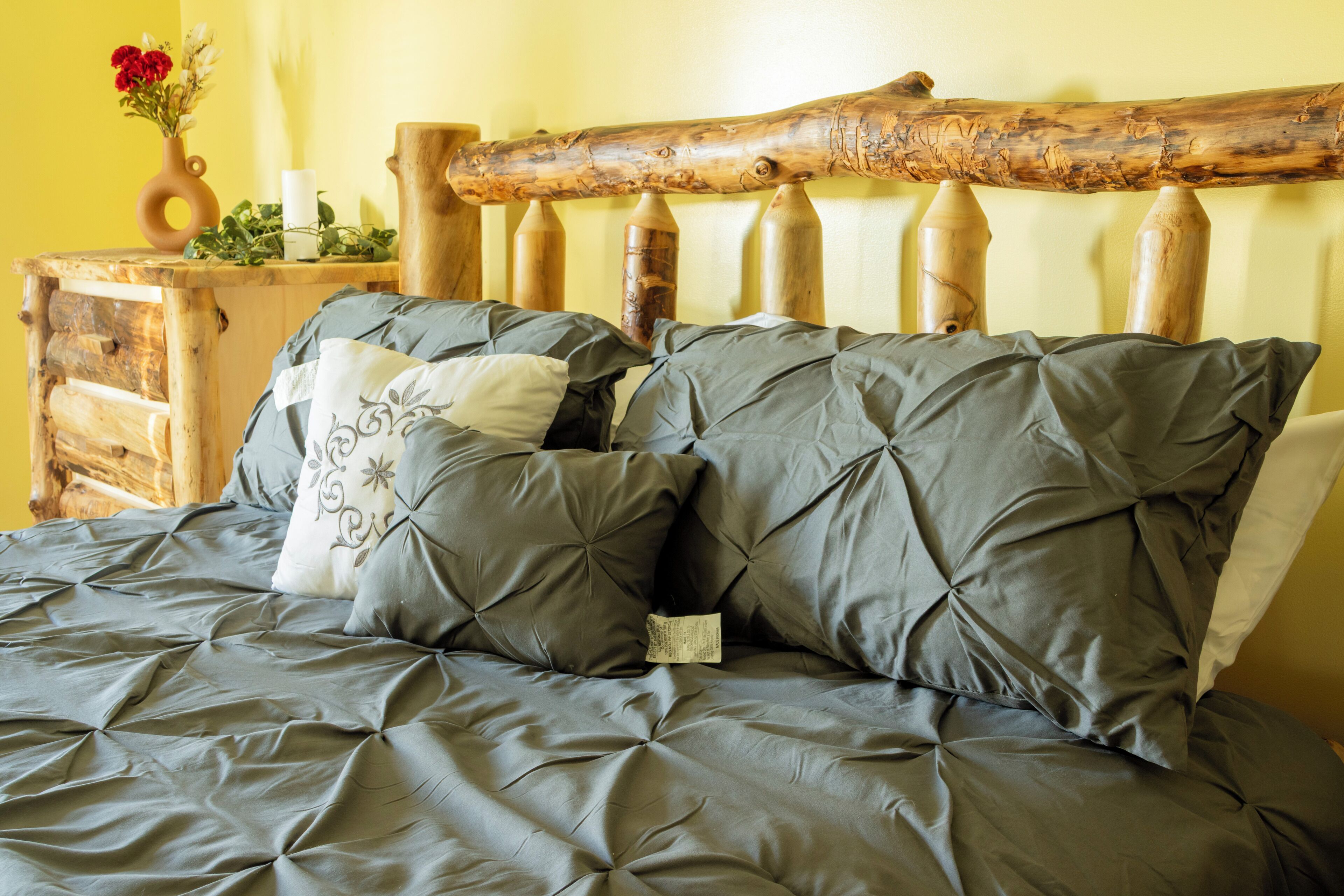 A bed with grey bedding and wooden headboard.