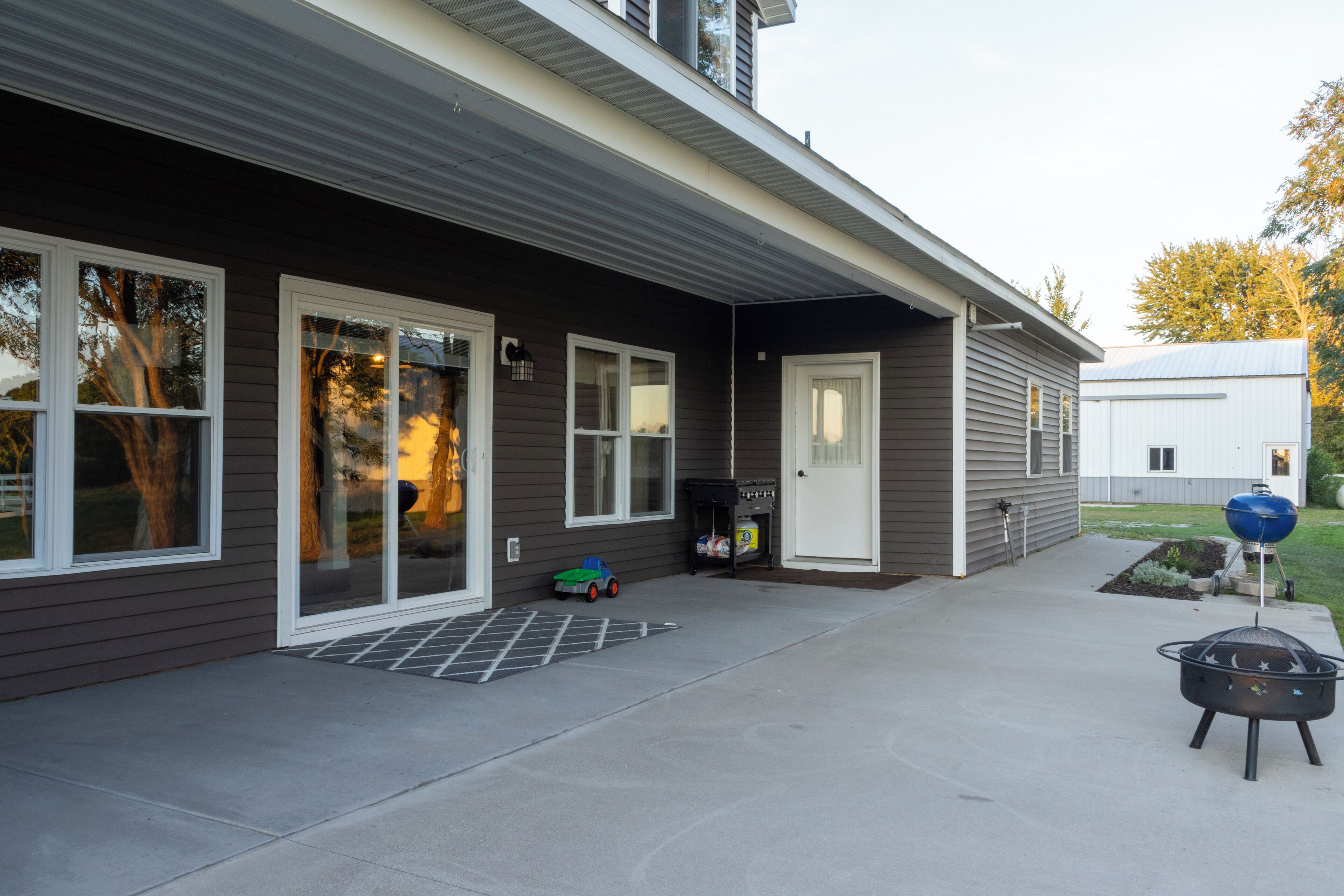 A modern house with a covered patio, a barbecue grill, and a toy car.