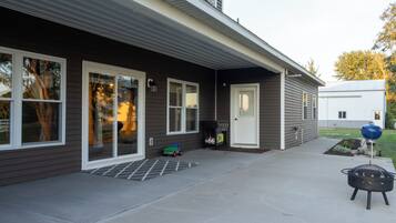 A modern house with a covered patio, a barbecue grill, and a toy car.