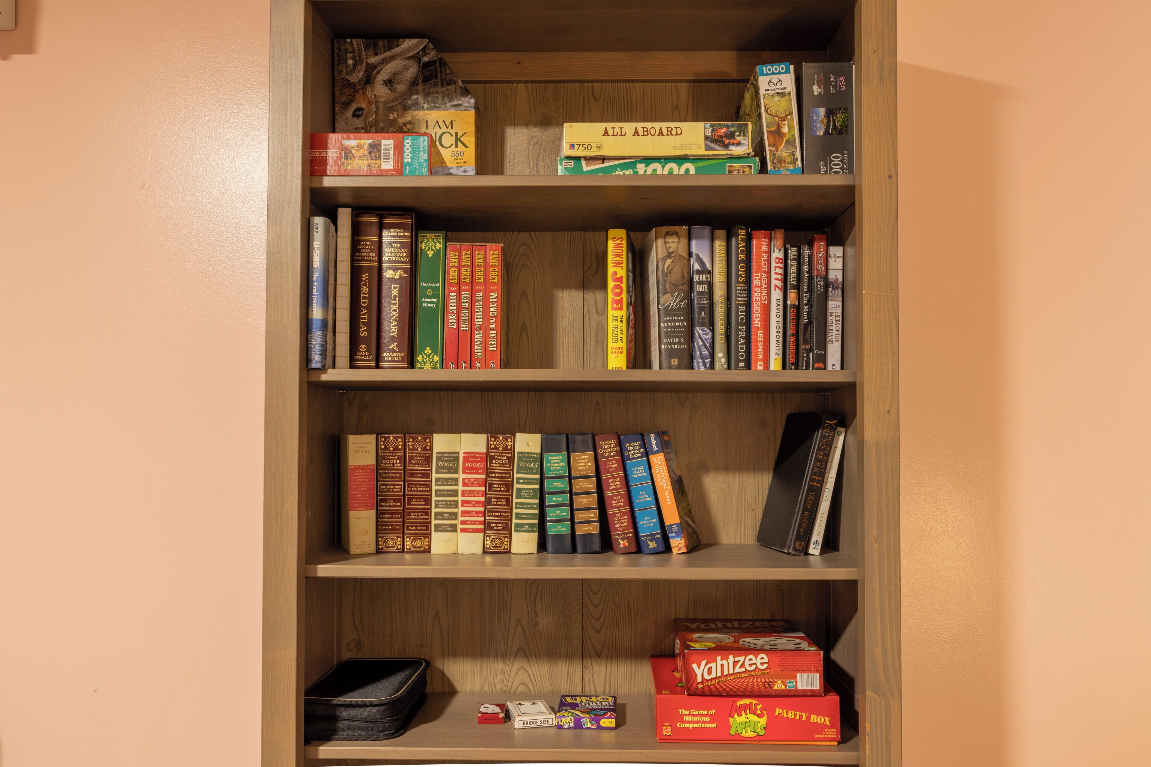 Une bibliothèque contenant divers livres et jeux, notamment une boîte de jeux de réflexion et une boîte de jeu de Yahtzee.