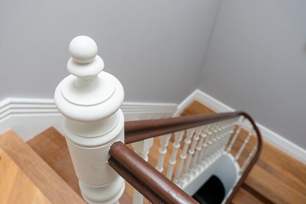A white wooden staircase with a wooden handrail and a white balustrade.