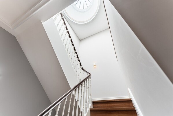 A modern staircase with white balusters and a wooden finish at the bottom.