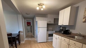 A kitchen with white cabinets, a refrigerator, an oven, and a coffee maker. - Cozy 2BR Loft Fast WiFi Parking (St. John's)