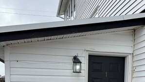 A small, single-story building with a black door and a white exterior. - Cozy 2BR Loft Fast WiFi Parking (St. John's)
