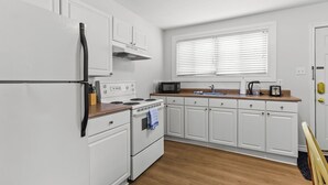 A compact kitchen with white cabinetry, a built-in oven, a microwave, and a toaster. - Bright 2BR Loft WiFi Parking (St. John's)