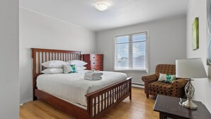 Une chambre à coucher avec un lit en bois, une commode, une chaise et une lampe.