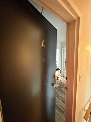 A dark door with the number 4, a brass doorknob, and a chain lock. - Modern 2BR Suite Parking Laundry (St. John's)
