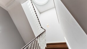A modern staircase with a glass railing and a skylight above.