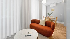 A modern living room with a sofa, a coffee table, and a dining area with chairs and a table.