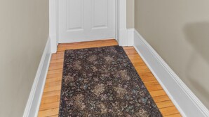 A hallway with a white door marked with the number 5, a wooden floor, and a dark patterned rug. - Midstream Manor 1BR Parking WiFi (St. John's)