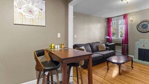 A dining area with a wooden table and chairs, a sofa, and a fireplace. - Midstream Manor 1BR Parking WiFi (St. John's)