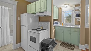 A compact kitchen with a stove, microwave, and green cabinets. - Chic Midstream Studio WiFi Parking (St. John's)