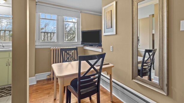 A dining area with a table, chairs, a television, and a large mirror on the wall. - Chic Midstream Studio WiFi Parking (St. John's)