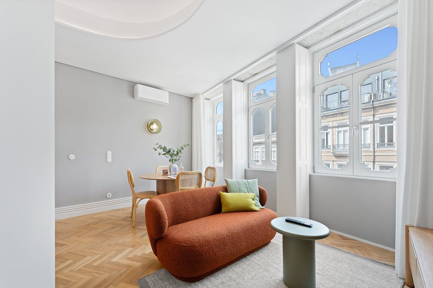 A modern living room with a sofa, a small table, and a dining area.