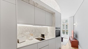 Eine moderne Küche mit Marmorarbeitsplatten, einem Einbauofen und Blick auf die Stadt durch große Fenster.
